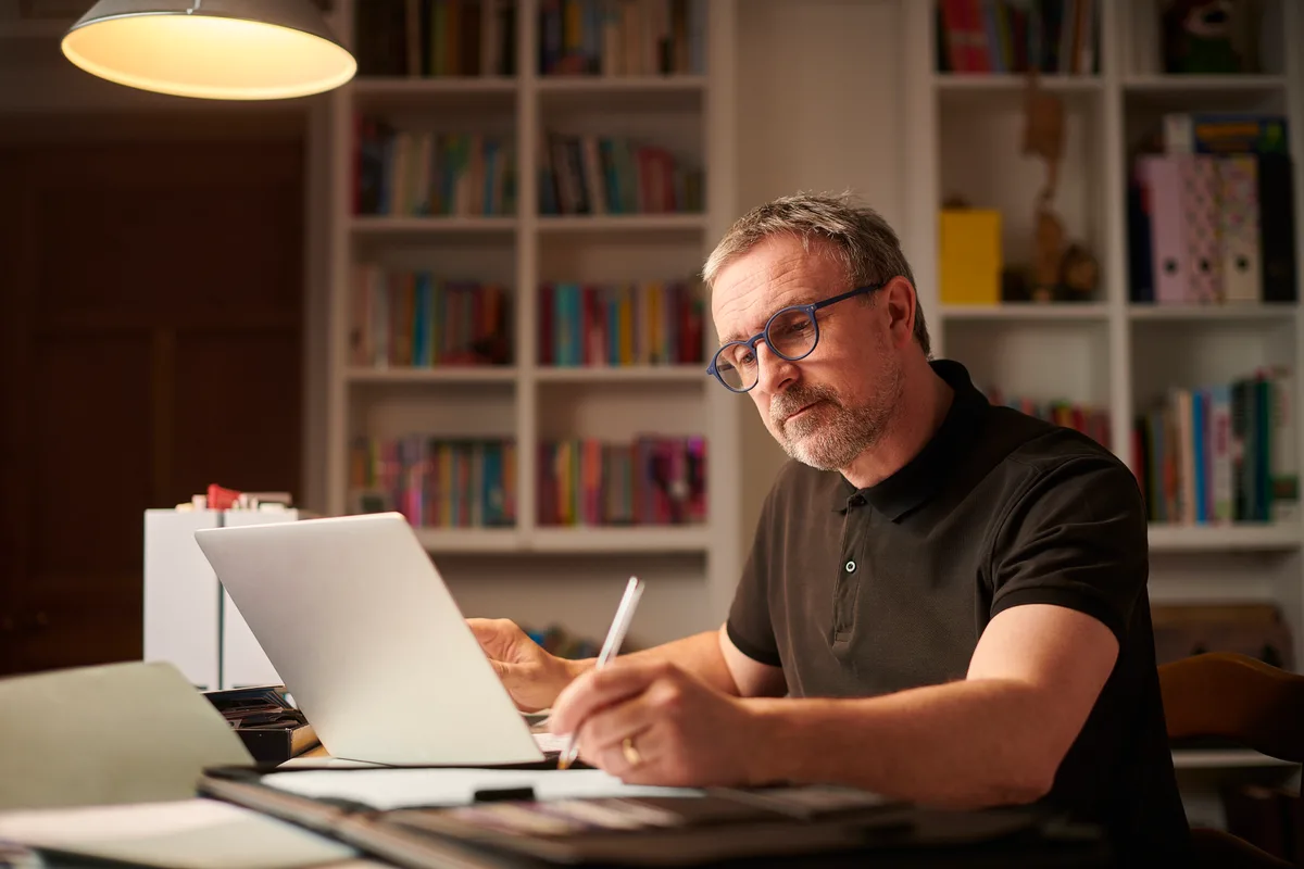Business owner teaching himself SEO on a laptop in his home office at night