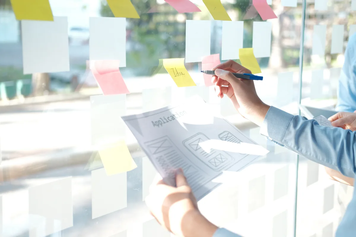 A content strategist grouping customer questions into topic clusters on a glass planning wall to decide page structure