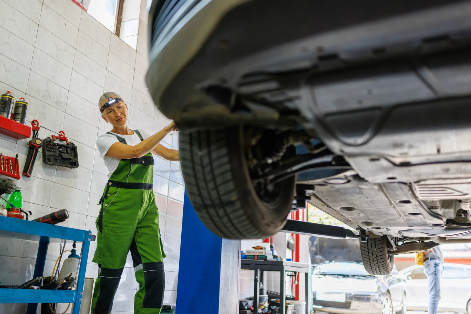 A technician working under an SUV raised on a lift in the Atlantic Motors service bay