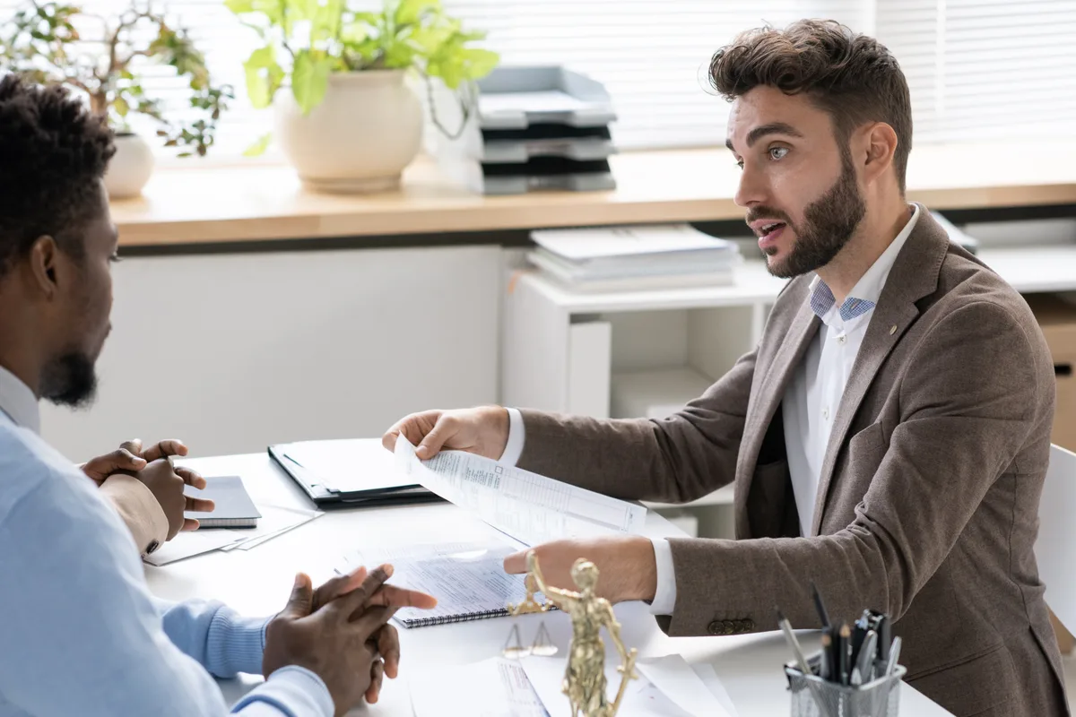 A bankruptcy attorney explaining filing options to a worried client across a desk in a law office