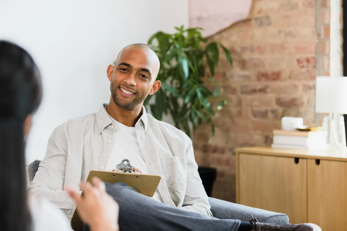 A counselor and client sitting across from each other during a warm therapy session in a calm office