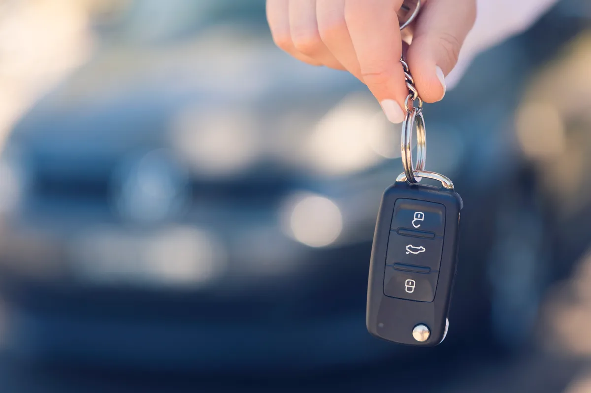 Salesperson handing keys to a buyer on a used car dealership showroom floor