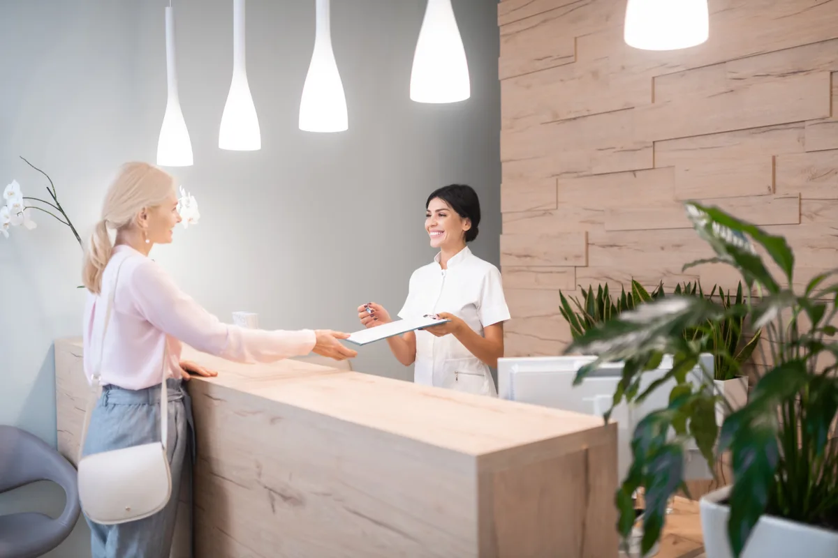 A spa front desk where a therapist checks in a client, illustrating the booking moment that spa marketing is built around