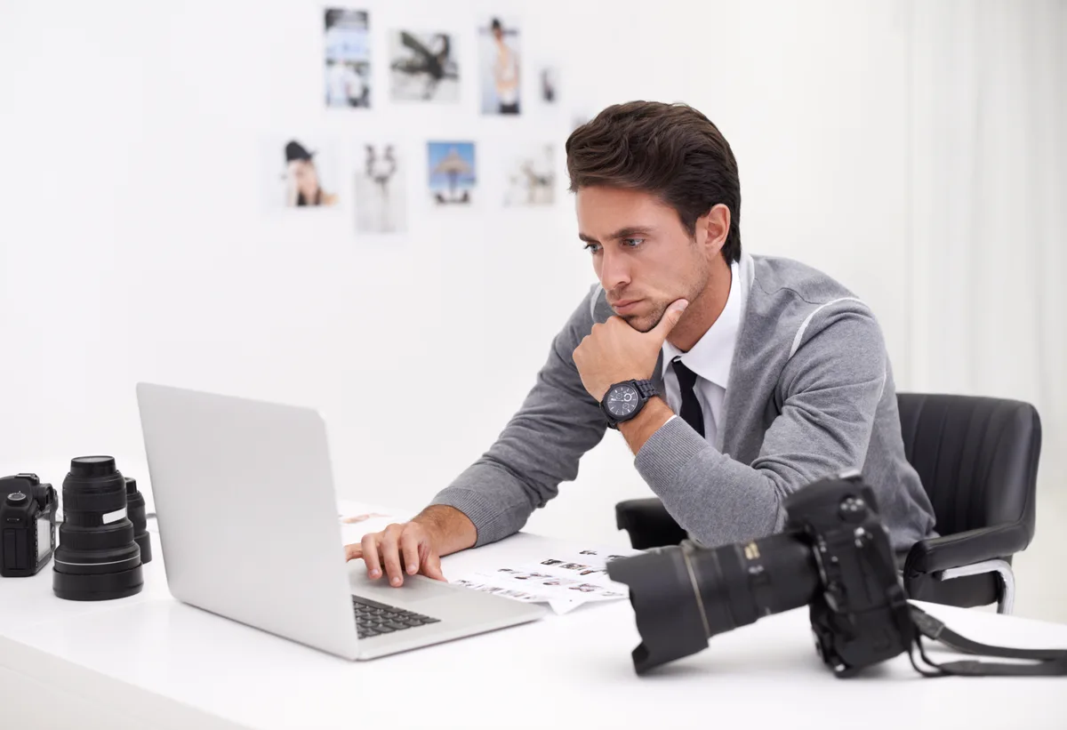 A photographer reviewing edited images and inquiry messages on a laptop in a bright studio