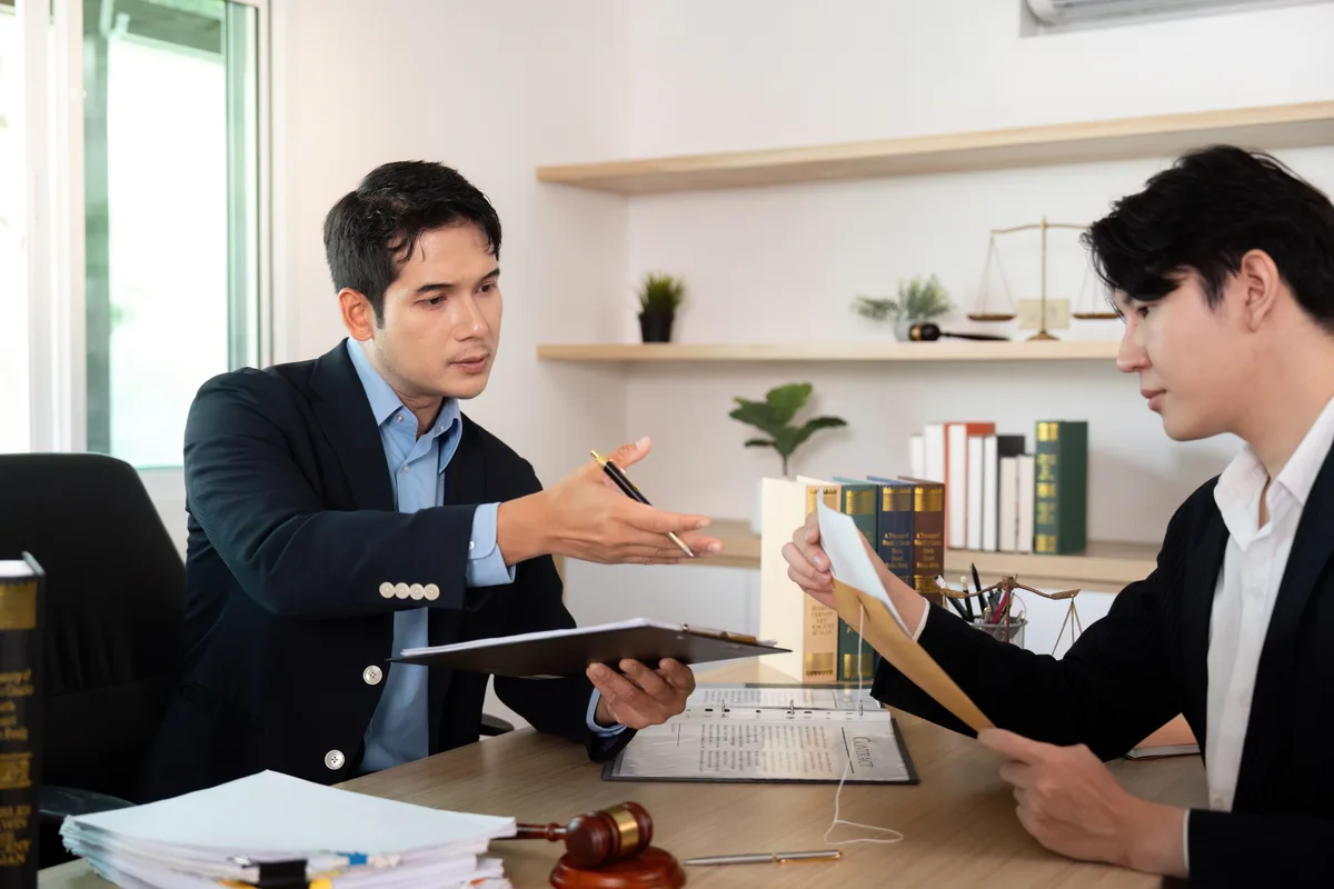 A workers' compensation attorney reviewing claim documents with an injured worker across a desk