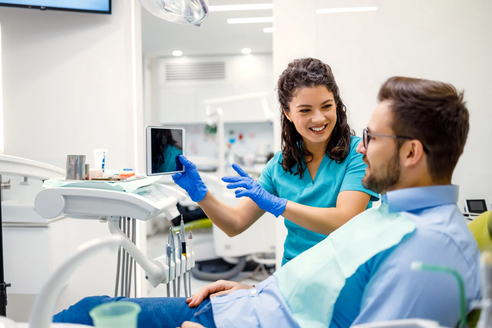 A dentist welcoming a patient and reviewing their care plan in a bright, modern dental practice