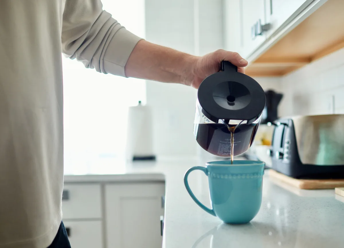 Pouring a fresh cup of Ember & Oak coffee in a bright kitchen