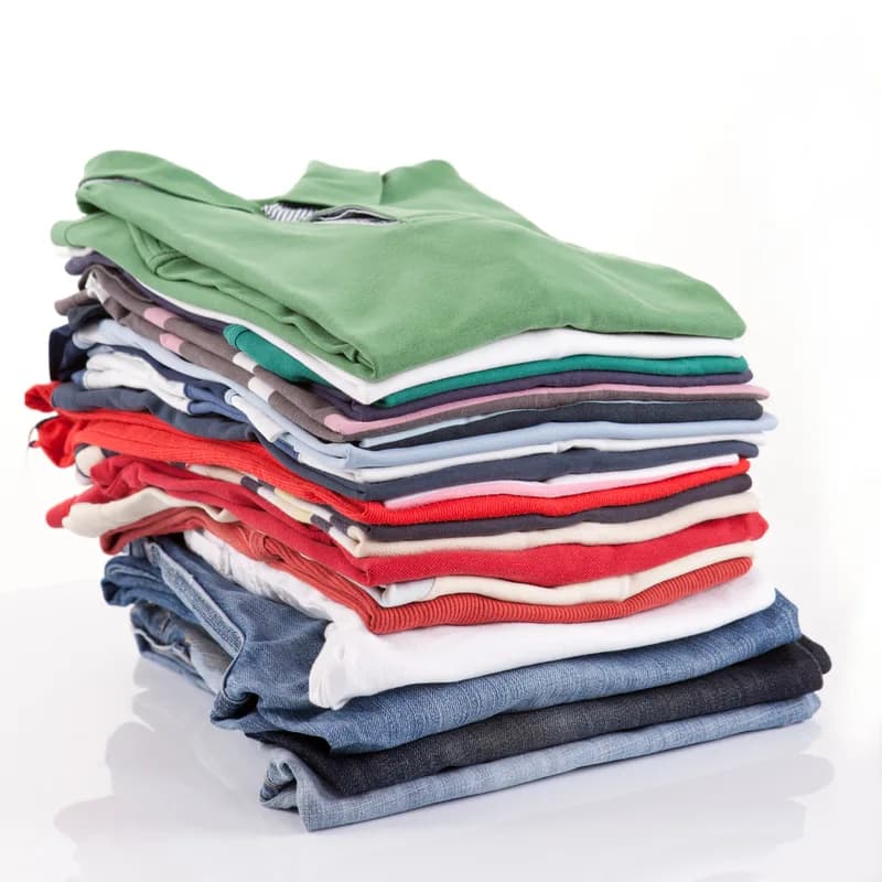 Folded stack of Field Trousers and denim in stone, olive and indigo on a white surface