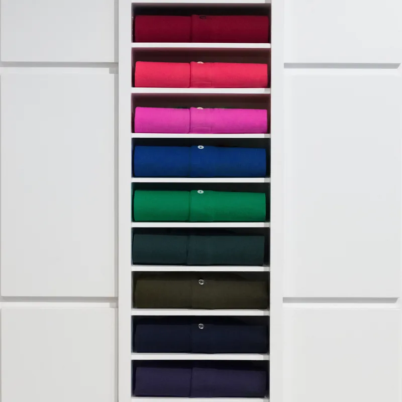 Oxford Button-Down shirts rolled and stacked by colour in white studio cubbies