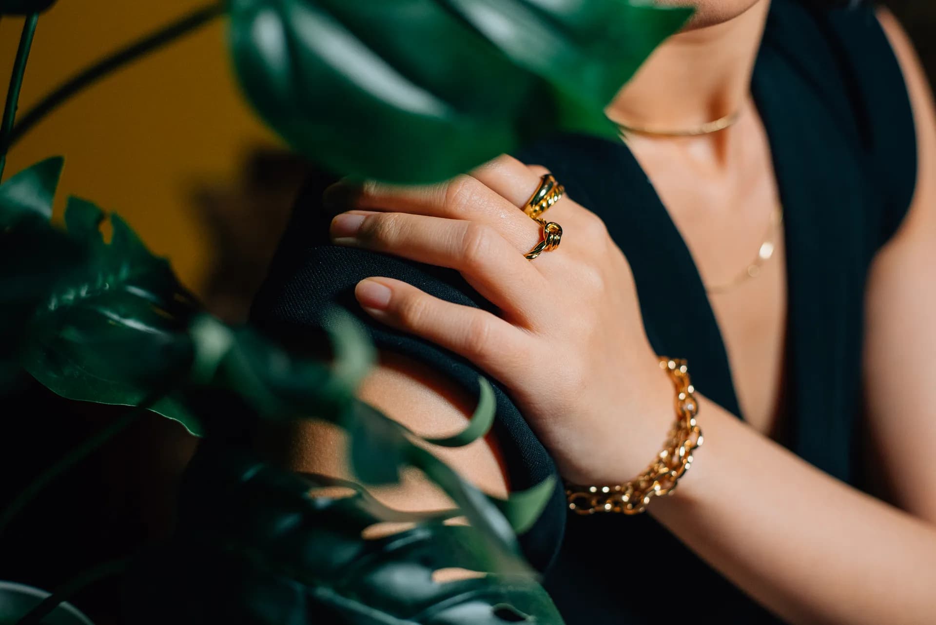 Model wearing layered Aurelia gold necklaces and a solitaire ring