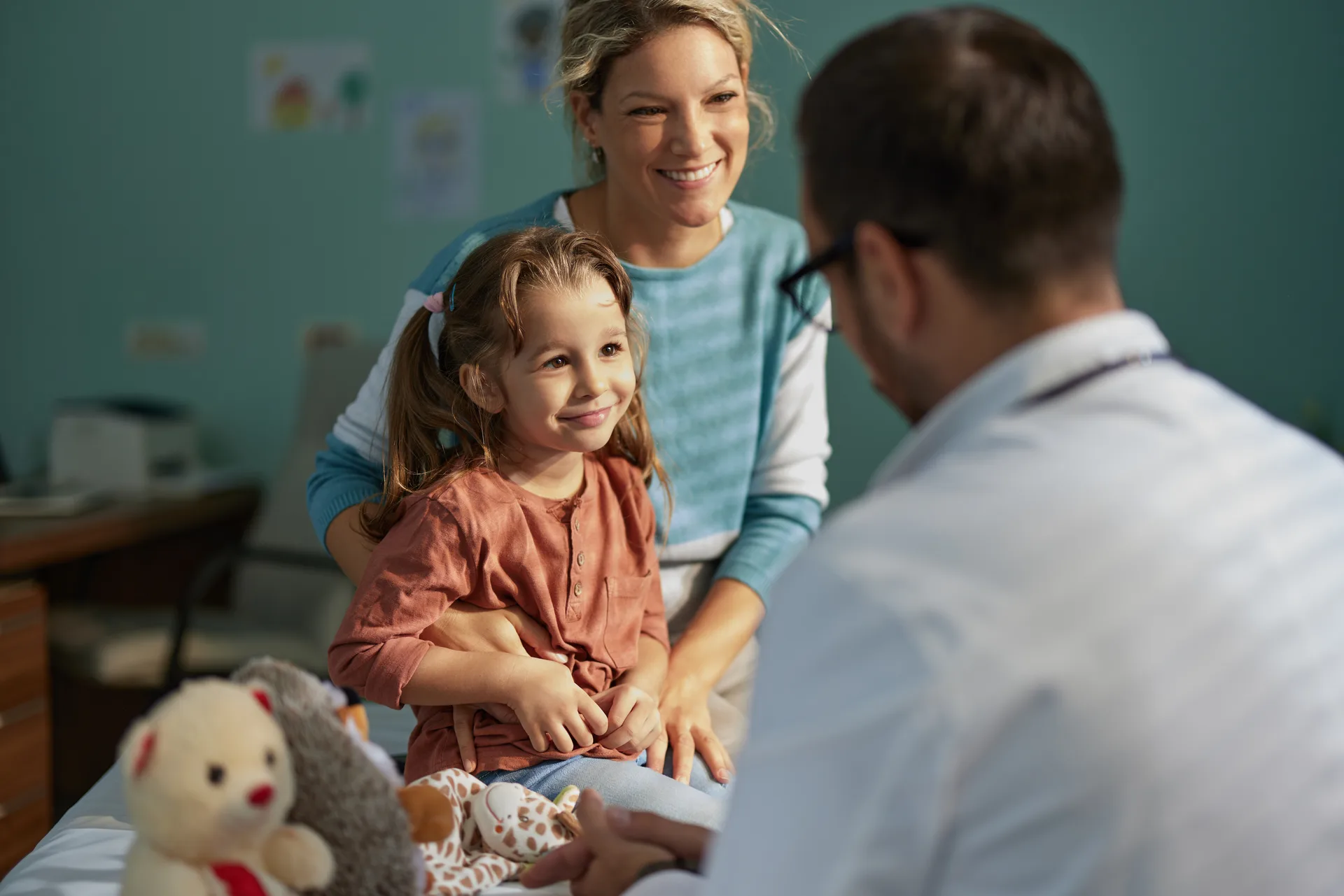 A girl smiling with her mother during a pediatric visit