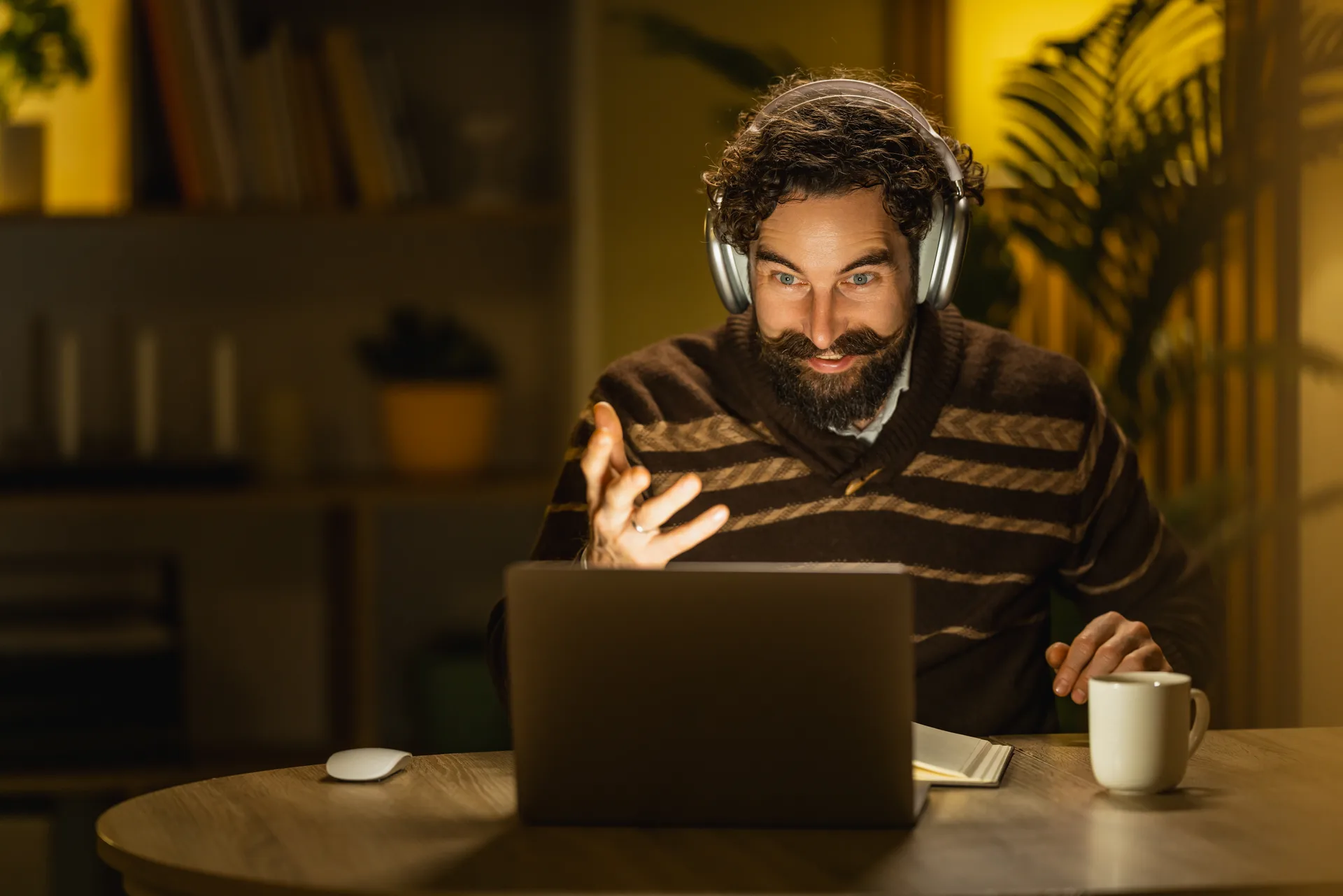 A man with headphones smiling during an evening video therapy session at home