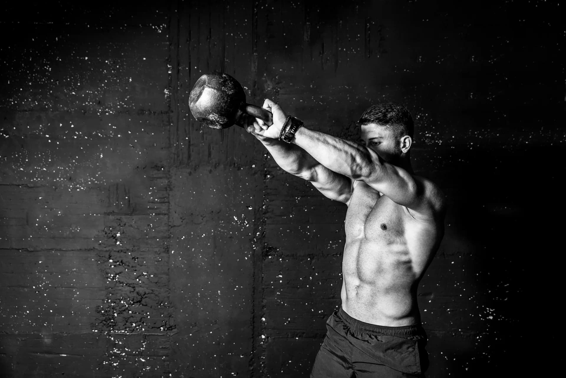 An athlete mid-swing with a kettlebell in dramatic light