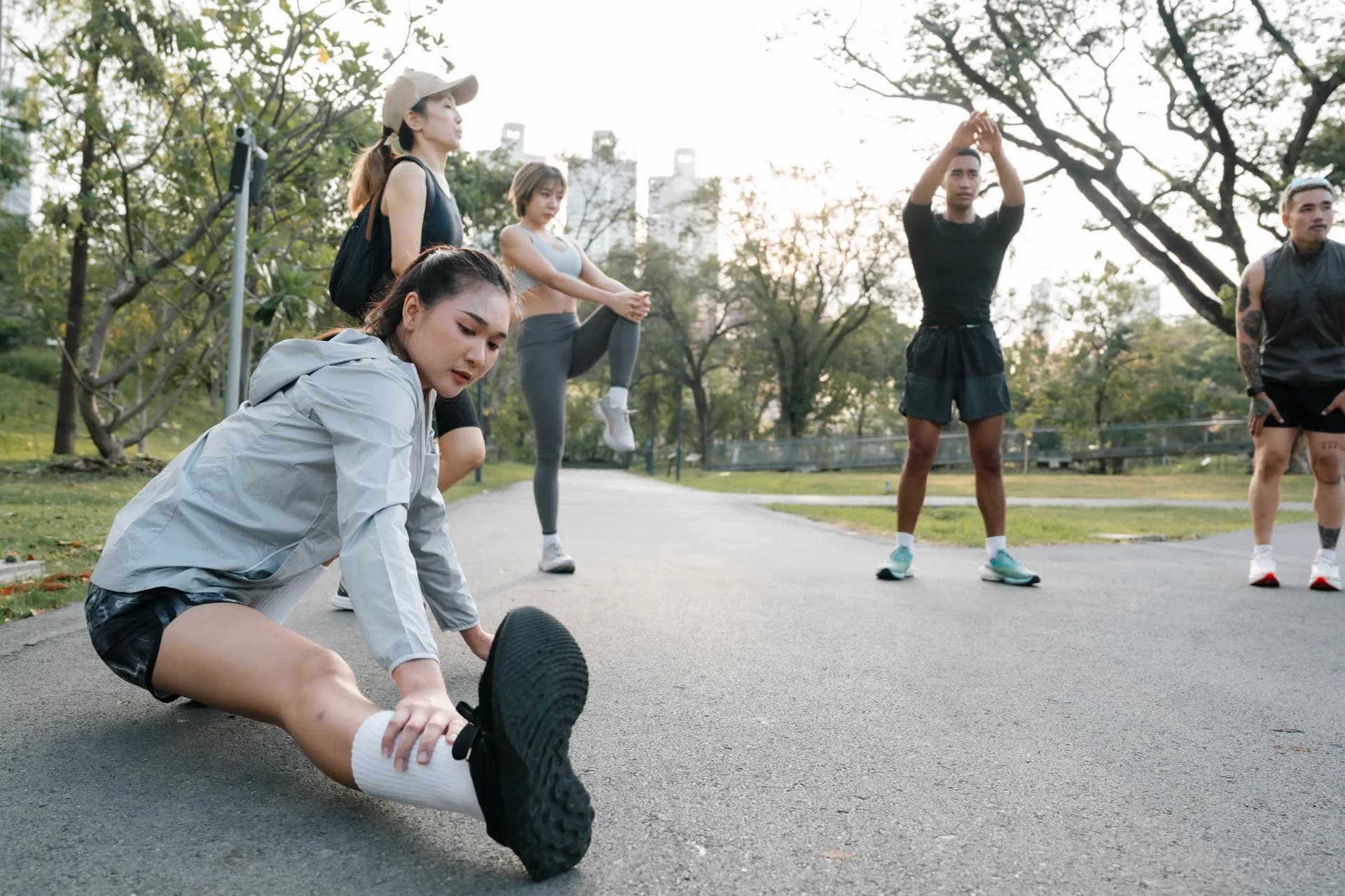 A diverse group of athletes stretching together outdoors at golden hour