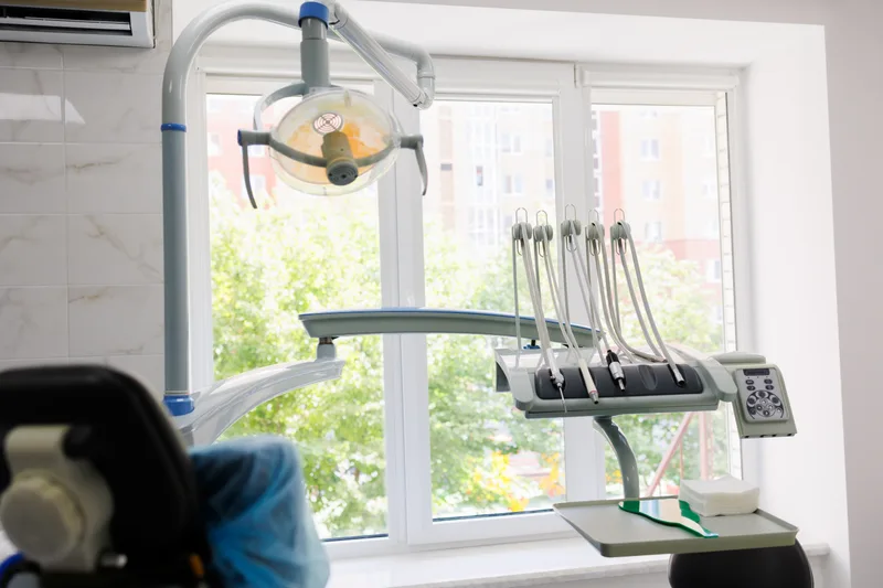 Dental chair beside a bright window with greenery outside