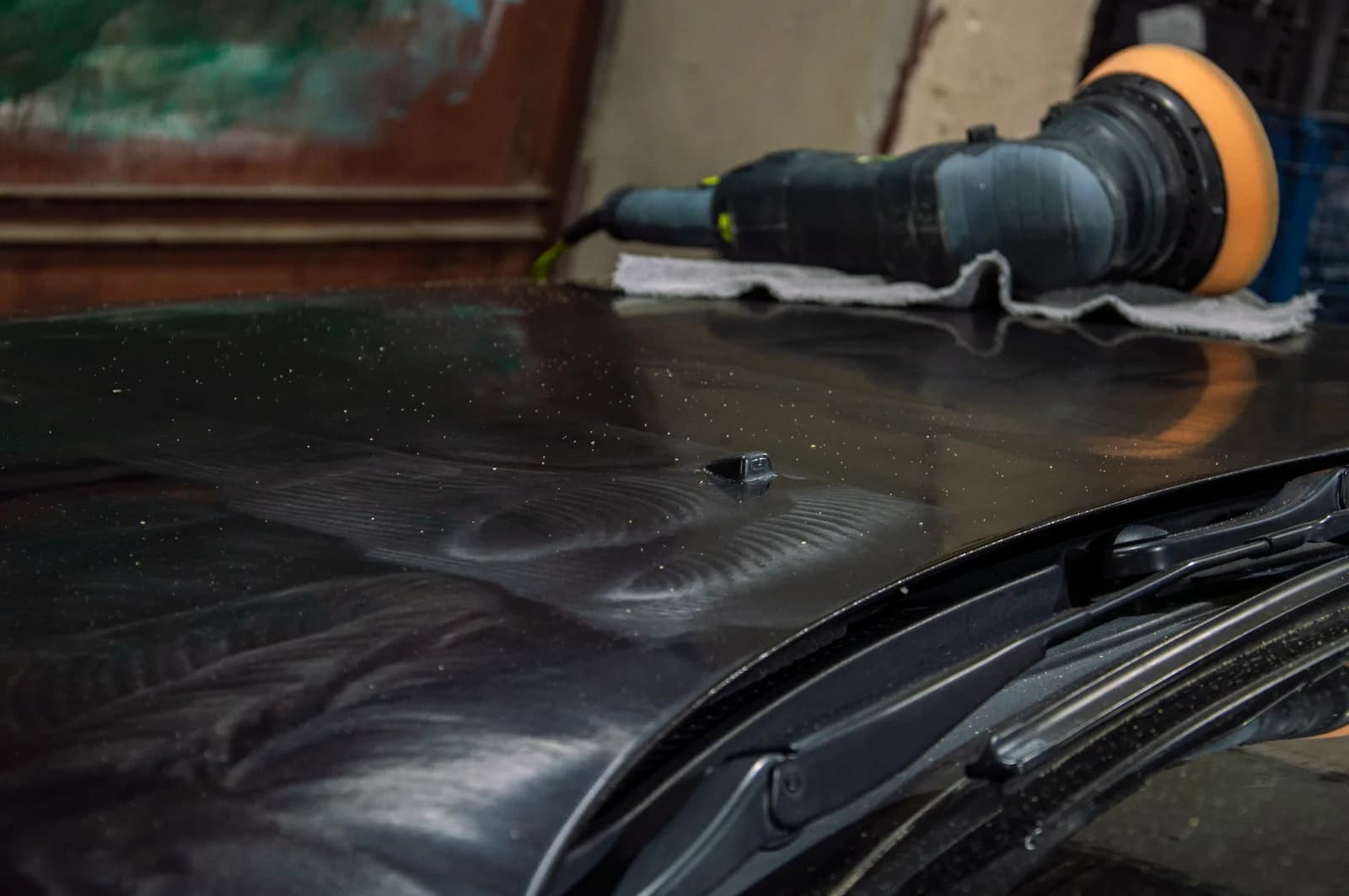 Detailer polishing a car to a high-gloss finish in a detailing shop