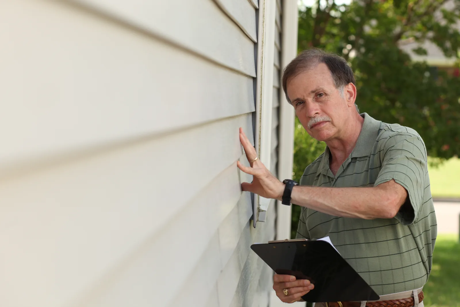 Home inspector examining a house with a clipboard