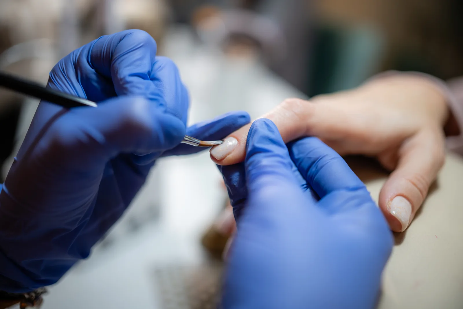 Manicurist applying polish during a manicure at a nail salon