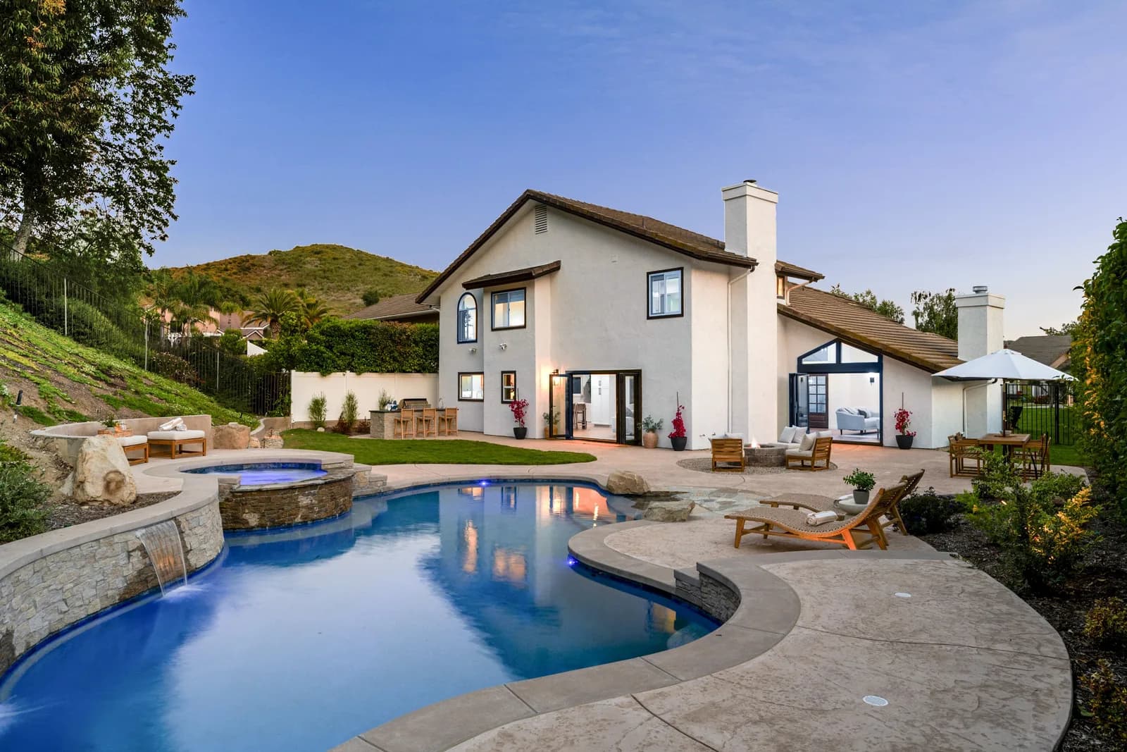Luxury inground swimming pool and patio in a landscaped backyard at dusk