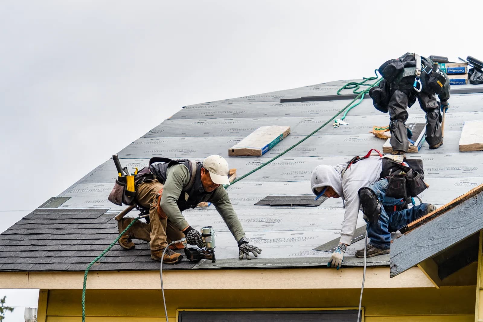 Roofing crew installing shingles on a residential roof