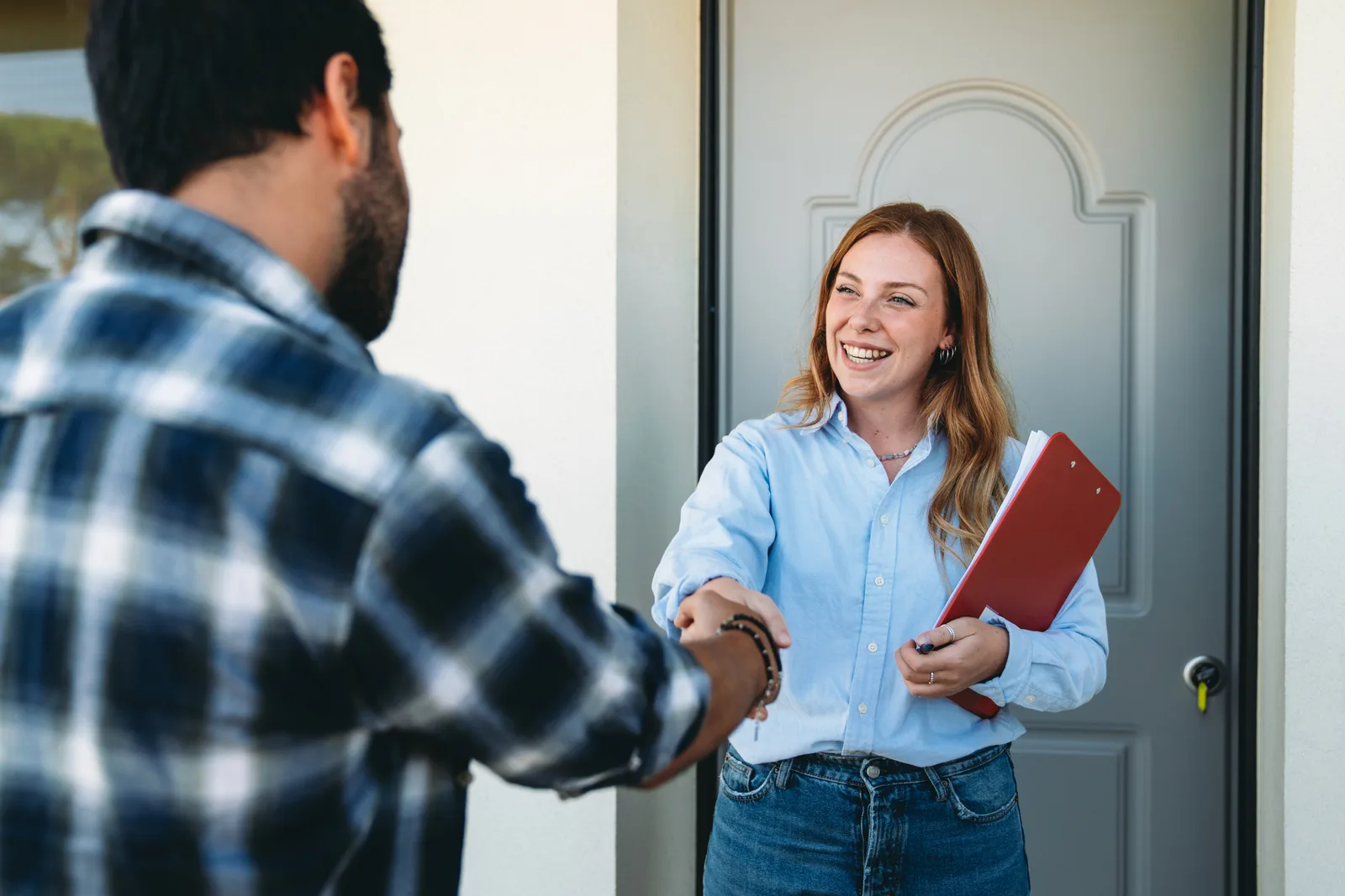 Investor shaking hands with a homeowner in front of a house
